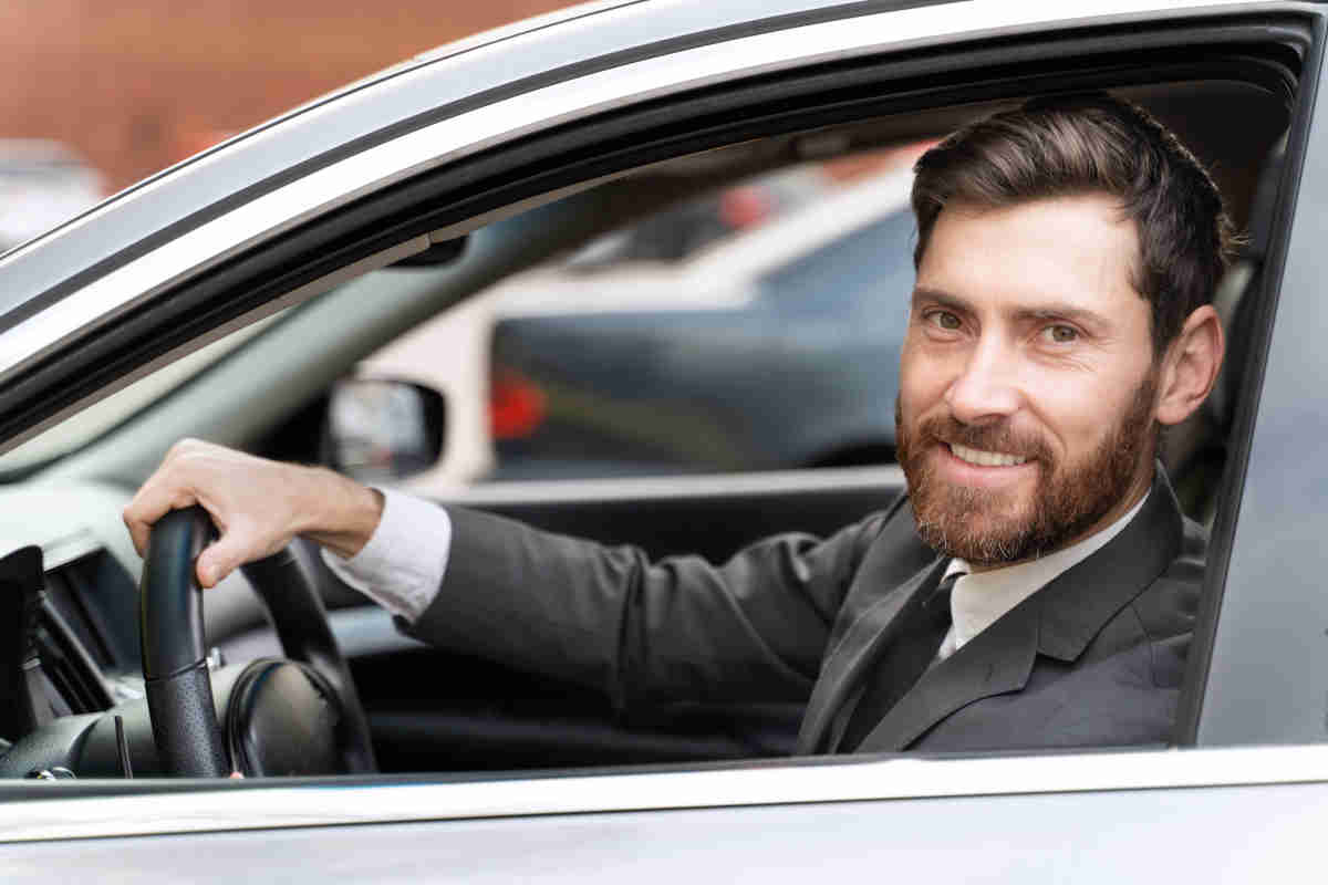 Ragazzo con la barba in abito elegante al voltante