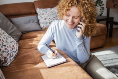 donna che parla a telefono e scrive su un foglio