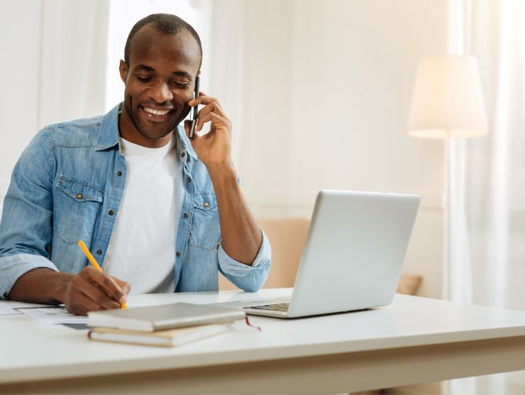 uomo che parla a telefono e scrive su un foglio